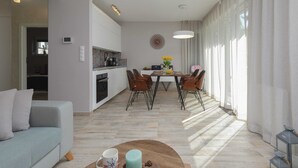 A modern living room with a sofa, coffee table, and dining area with chairs and a table.