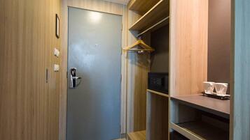 A compact room with a wooden door, a small shelf with a microwave, and a hanging coat rack.