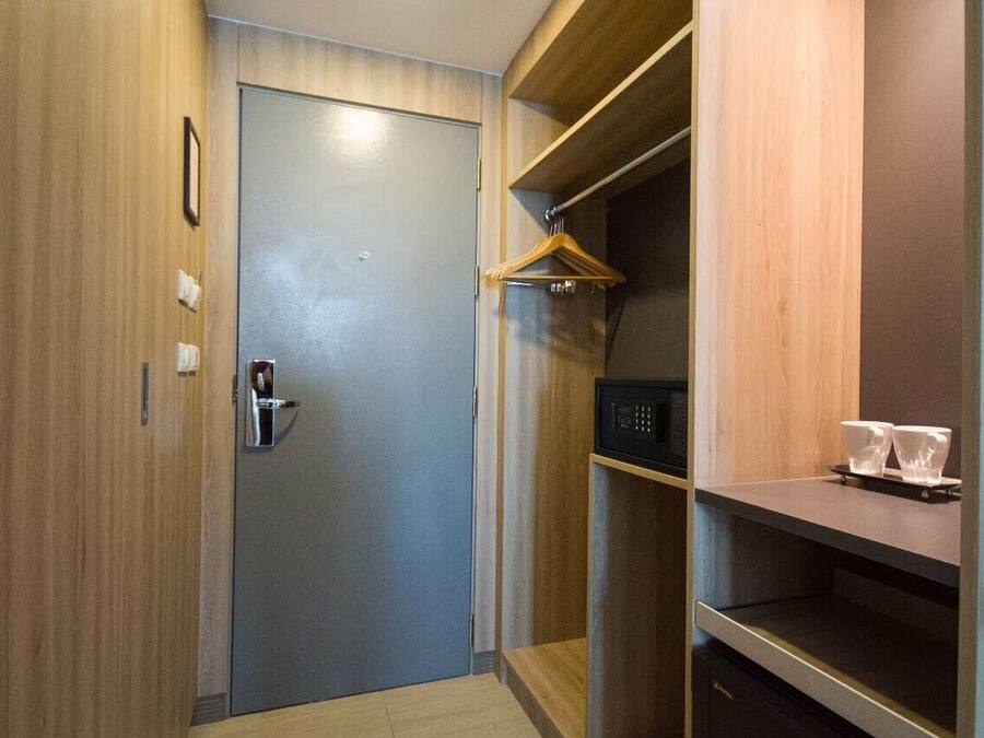 A compact room with a wooden door, a small shelf with a microwave, and a hanging coat rack.