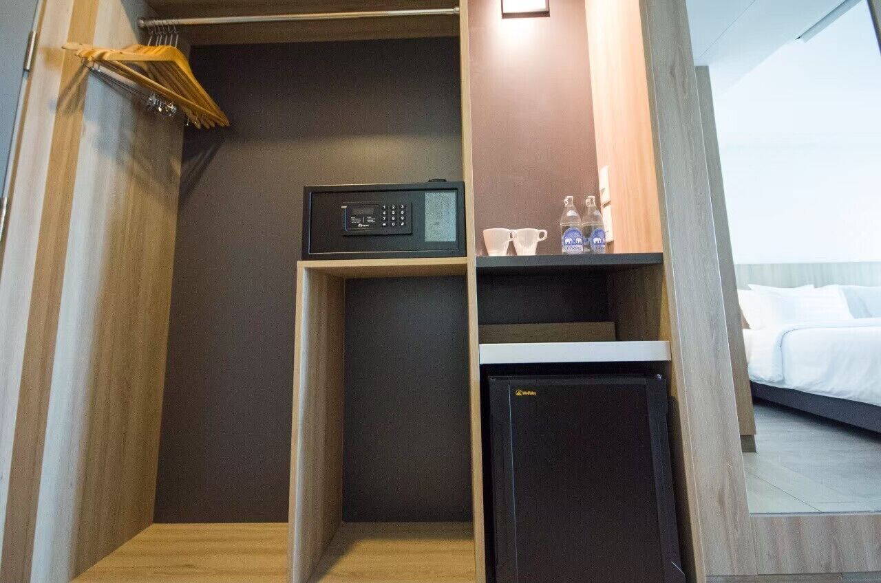 A compact hotel room with a kitchenette, a bed, and a small seating area.