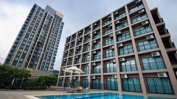 Um edifício de apartamentos moderno com piscina e área de estar ao ar livre.