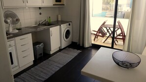 Une cuisine compacte équipée d’un lave-linge, d’un four à micro-ondes et d’un coin repas avec une table et des chaises.