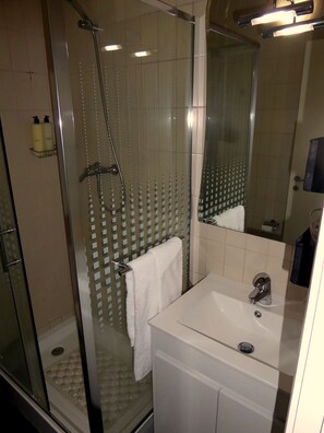 Une salle de bain moderne avec une douche à parois de verre, un lavabo blanc et un miroir.