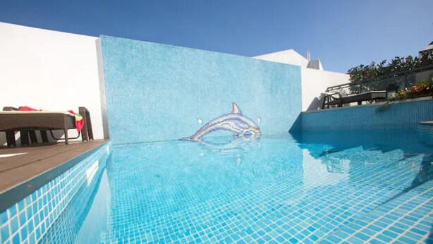 Une piscine dont le mur est décoré d’une mosaïque représentant un dauphin.