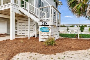 A beachfront property with a white exterior, a numbered address sign, and a sign indicating 'Beachton Breeze' on St. George Island. - Beach View, Private Pool, 4 BR Private Home (St George Island)