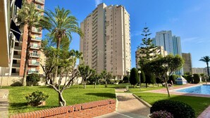 A residential area with a tall apartment building, a swimming pool, and well-maintained greenery.
