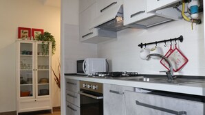 A modern kitchen with white cabinets, a built-in oven, a microwave, and a stainless steel sink. - Holiday apartment Two room apartment with pool (Lazise)