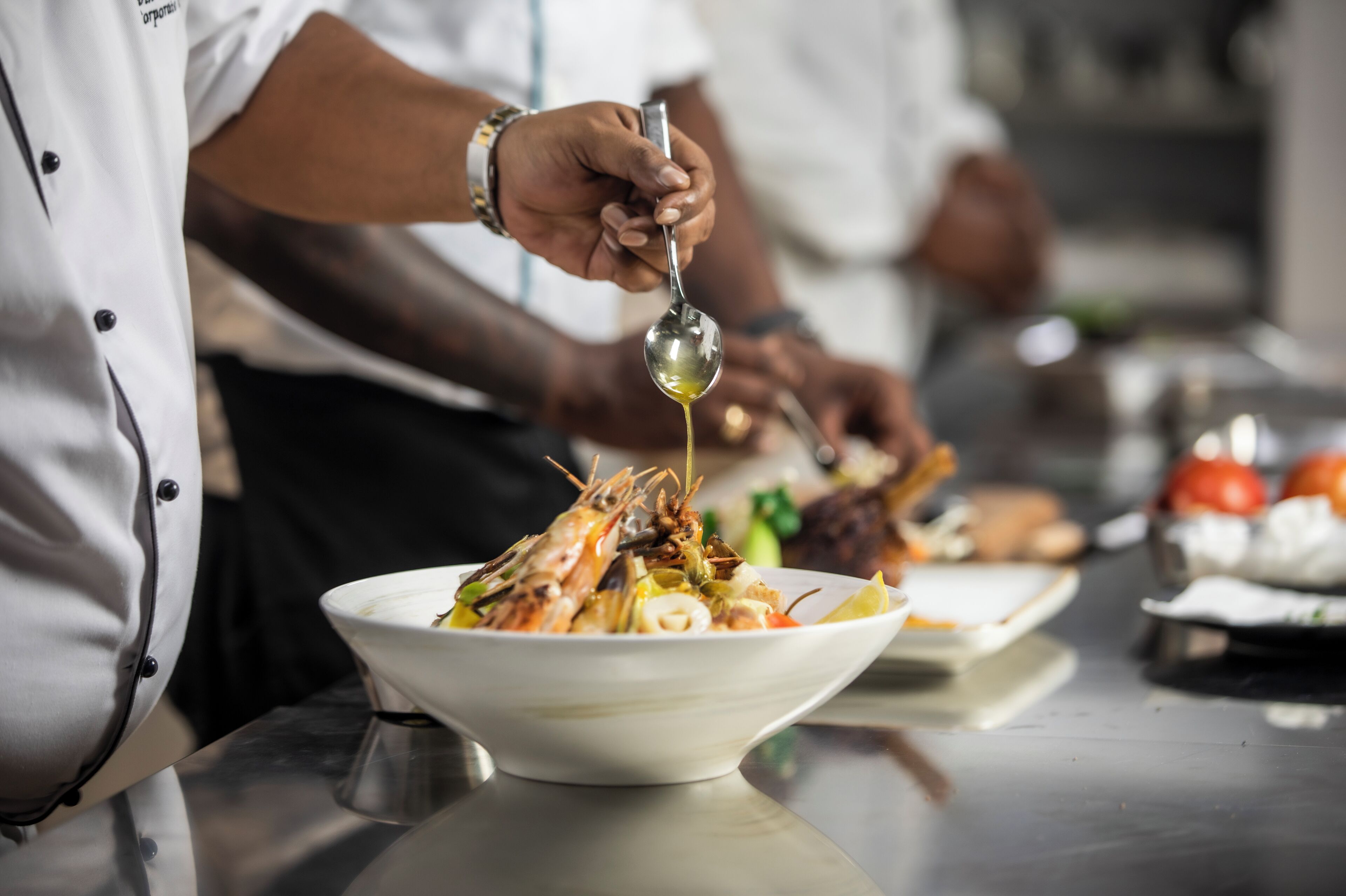 A chef preparing a dish with shrimp and vegetables in a professional kitchen setting.
