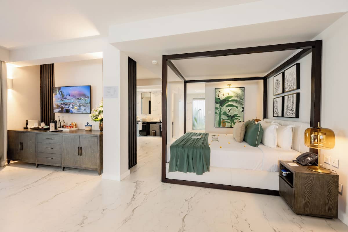Een moderne hotelkamer met een bed, nachtkastje en uitzicht op de badkamer.