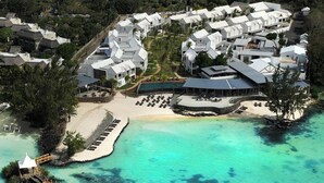 An aerial view of a resort with multiple white buildings, a sandy beach, and a clear turquoise sea. - Sea Diamond Boutique Hotel & Spa by Sea Resorts (Calodyne)