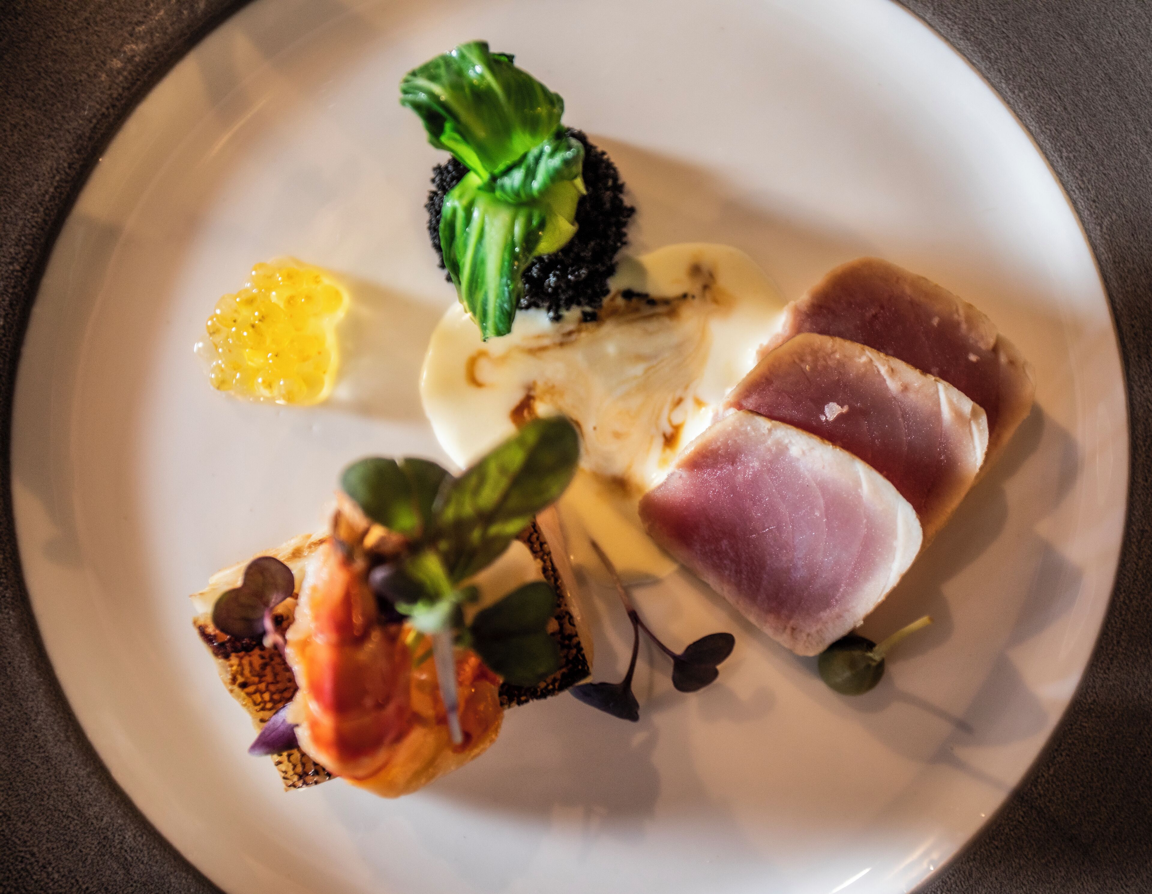A plate with various food items including a piece of meat, a green vegetable, and a yellow sauce.