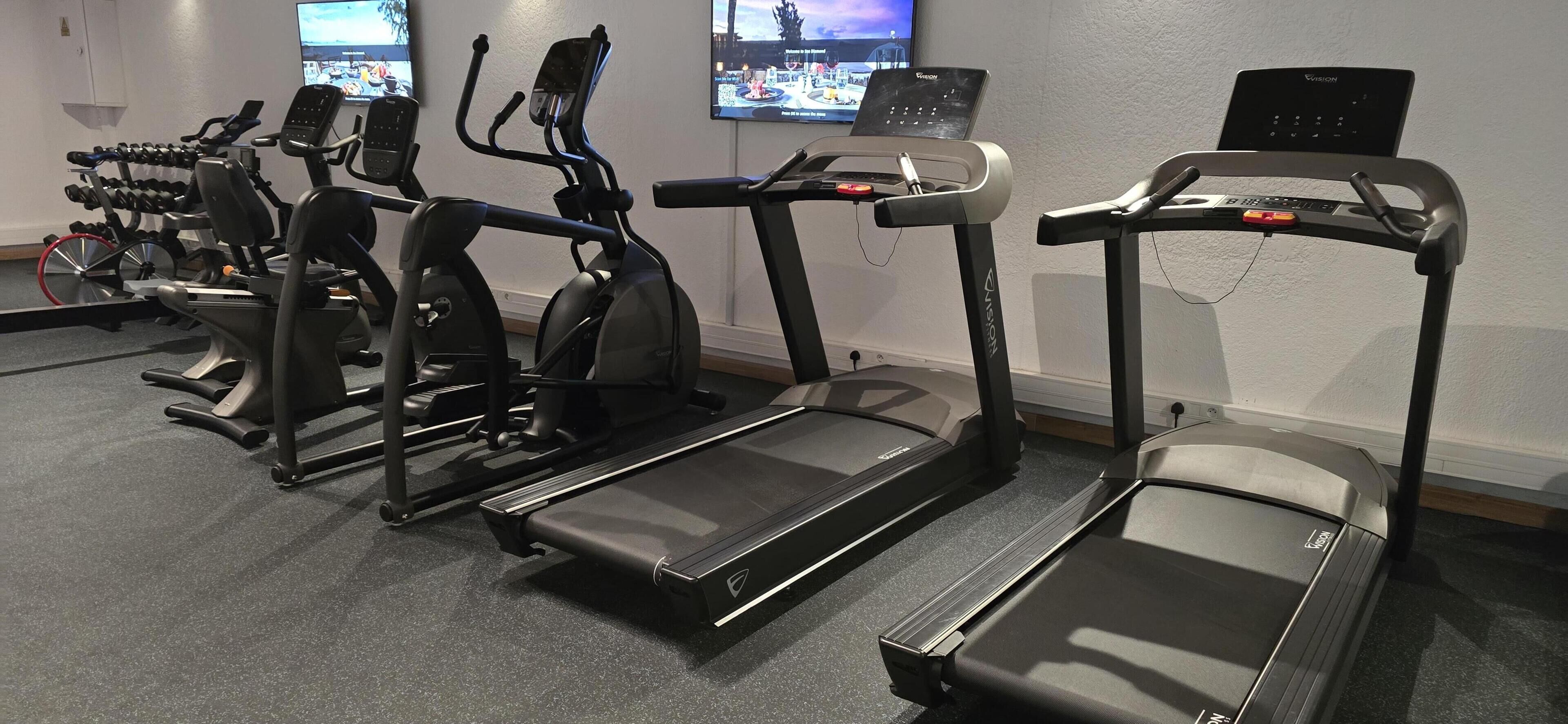 Un gimnasio con cintas de correr, elípticas y pesas.