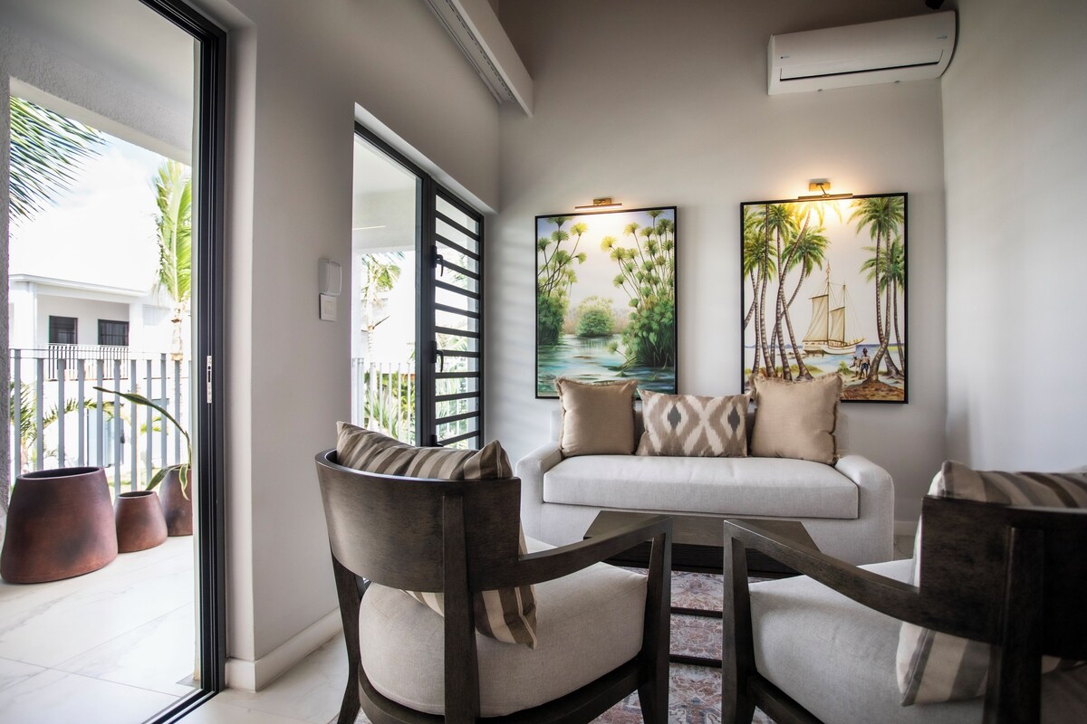 A modern living room with a sofa, chairs, and artwork on the wall.