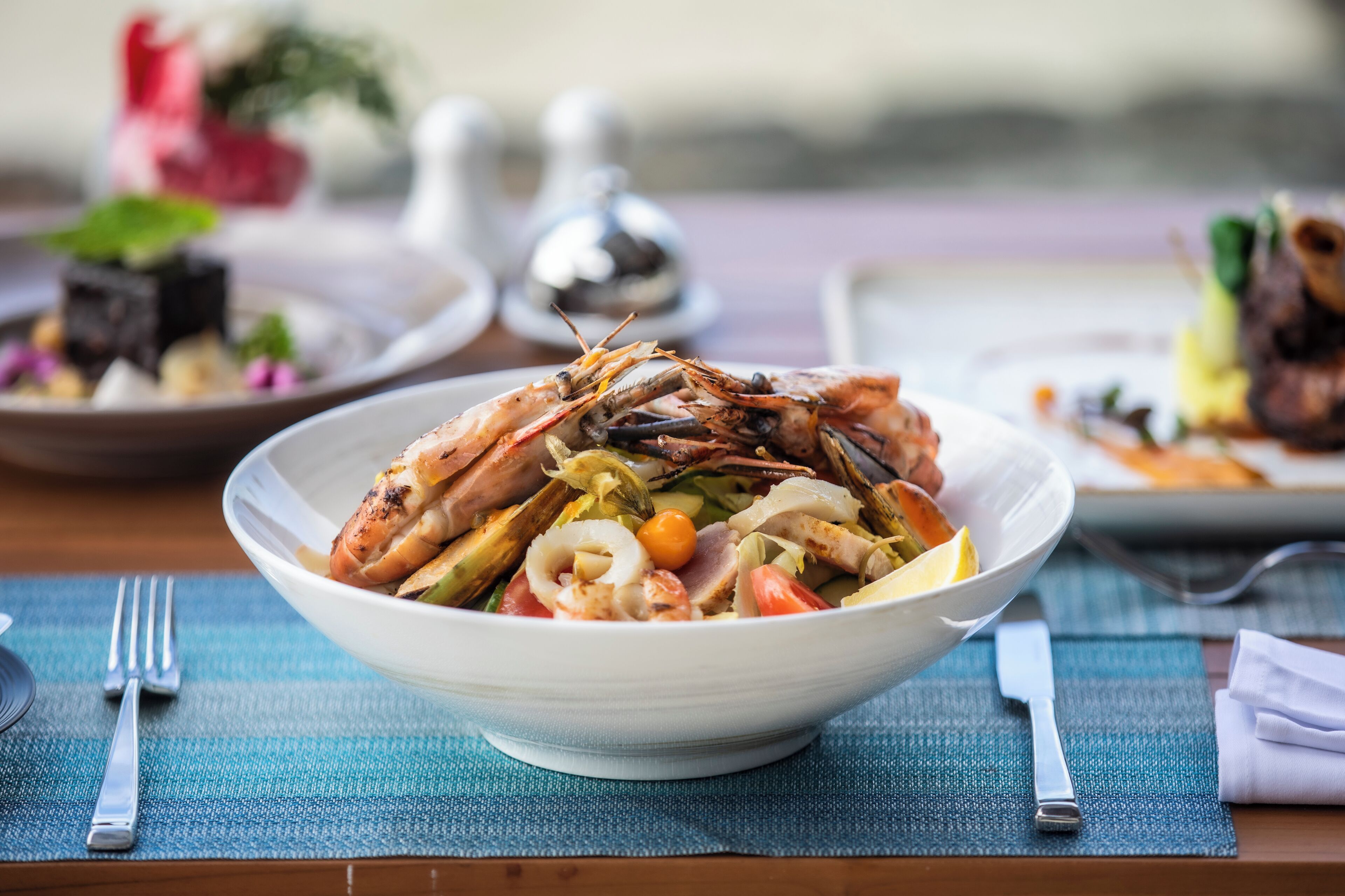 Prato de mariscos numa tigela sobre uma mesa com um jogo americano azul.