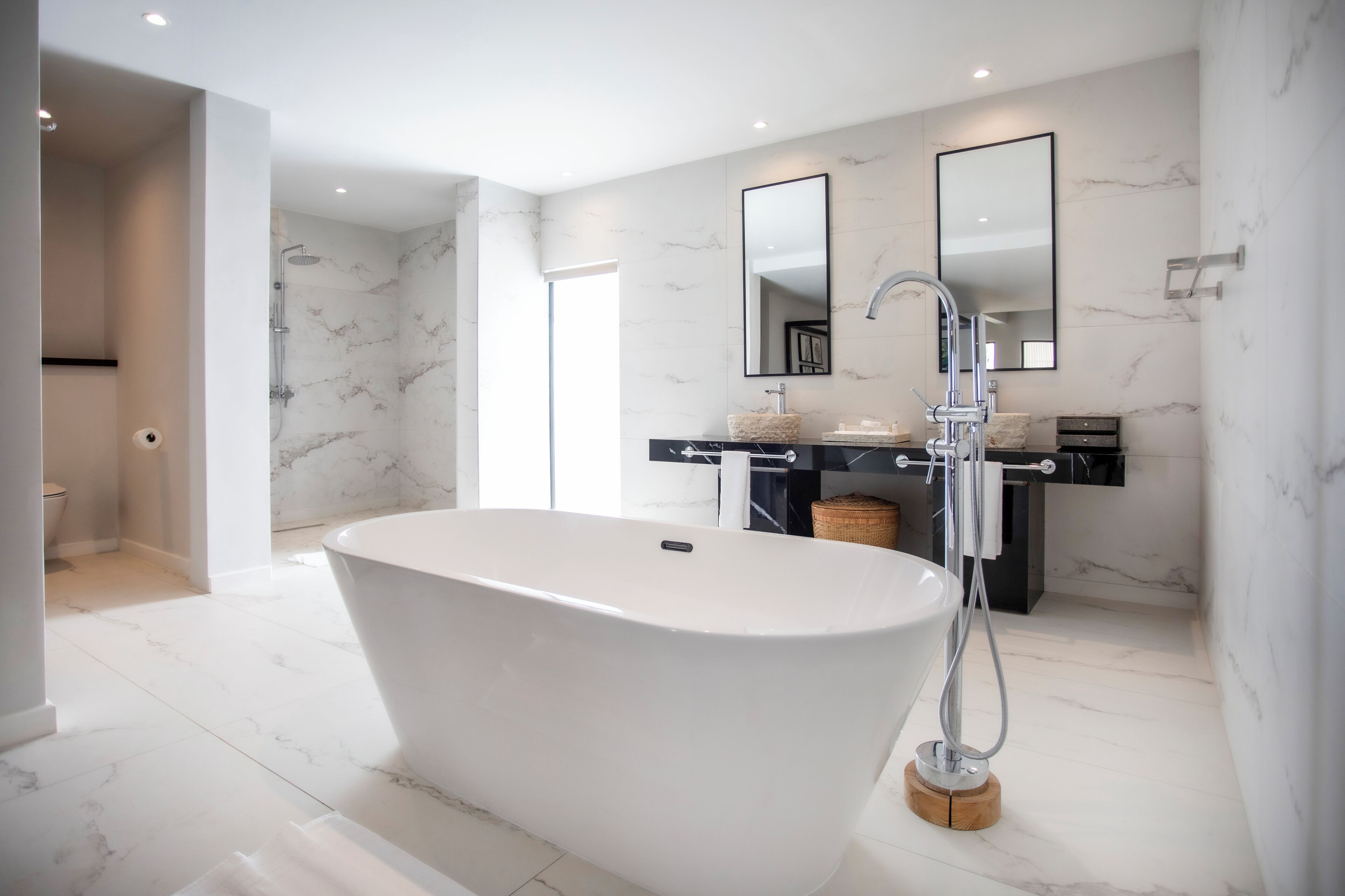 Une salle de bain moderne avec une baignoire sur pieds, un meuble-lavabo avec un miroir et des murs en marbre.