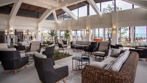 A spacious indoor area with high ceilings, large windows, and a variety of seating arrangements including sofas and chairs. - Sea Diamond Boutique Hotel & Spa by Sea Resorts (Calodyne)