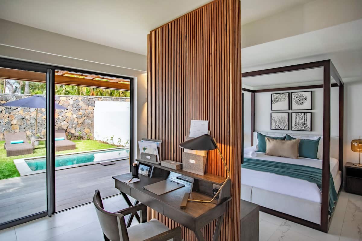 Een moderne slaapkamer met een bed, bureau en uitzicht op een zwembad en een terras.