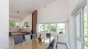 A modern kitchen with a large dining table, a brick chimney, and large windows. - Villa Green Castle (Omis)