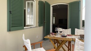 A dining area with a wooden table and chairs, a window with green shutters, and a view into the adjacent room. - Il Poggio, an exclusive location with parking (Firenze)