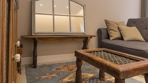 A living room with a grey sofa, a wooden coffee table, a patterned rug, and a large mirror on a wooden stand. - Il Poggio, an exclusive location with parking (Firenze)