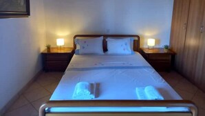 A hotel room with a wooden ceiling, a bed with white linens, two bedside tables with lamps, and a wardrobe.
