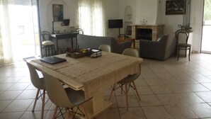 Un espace repas comprenant une table, des chaises, un téléviseur, une cheminée et un lustre.