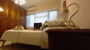 Une chambre à coucher comprenant un lit, une armoire en bois, une table de chevet et un téléviseur.