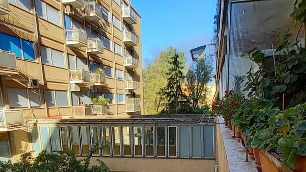Un immeuble à plusieurs étages doté de balcons et d’un jardin sur le toit.