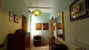 Un couloir étroit avec une commode en bois, un téléphone et des œuvres d’art encadrées accrochées aux murs.