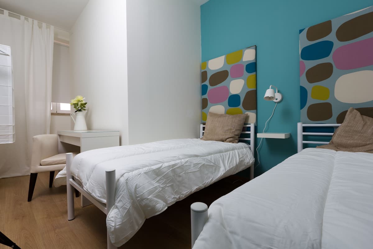 A hotel room with two beds, a desk, and a chair.