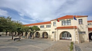 Ein Gebäude mit einem Ziegeldach, Bogenfenstern und einer Fahnenstange mit Flaggen.