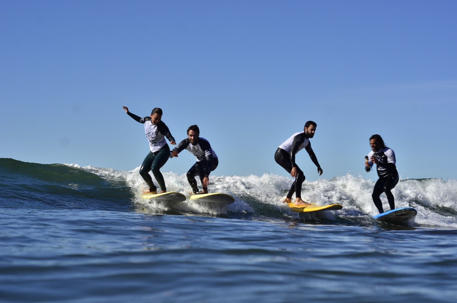 Cuatro personas surfeando una ola.