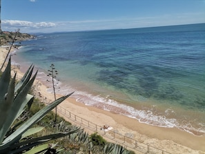 A coastal beach with clear waters, sandy shore, and a railing. - Turismo do Século Guest House (Cascais)