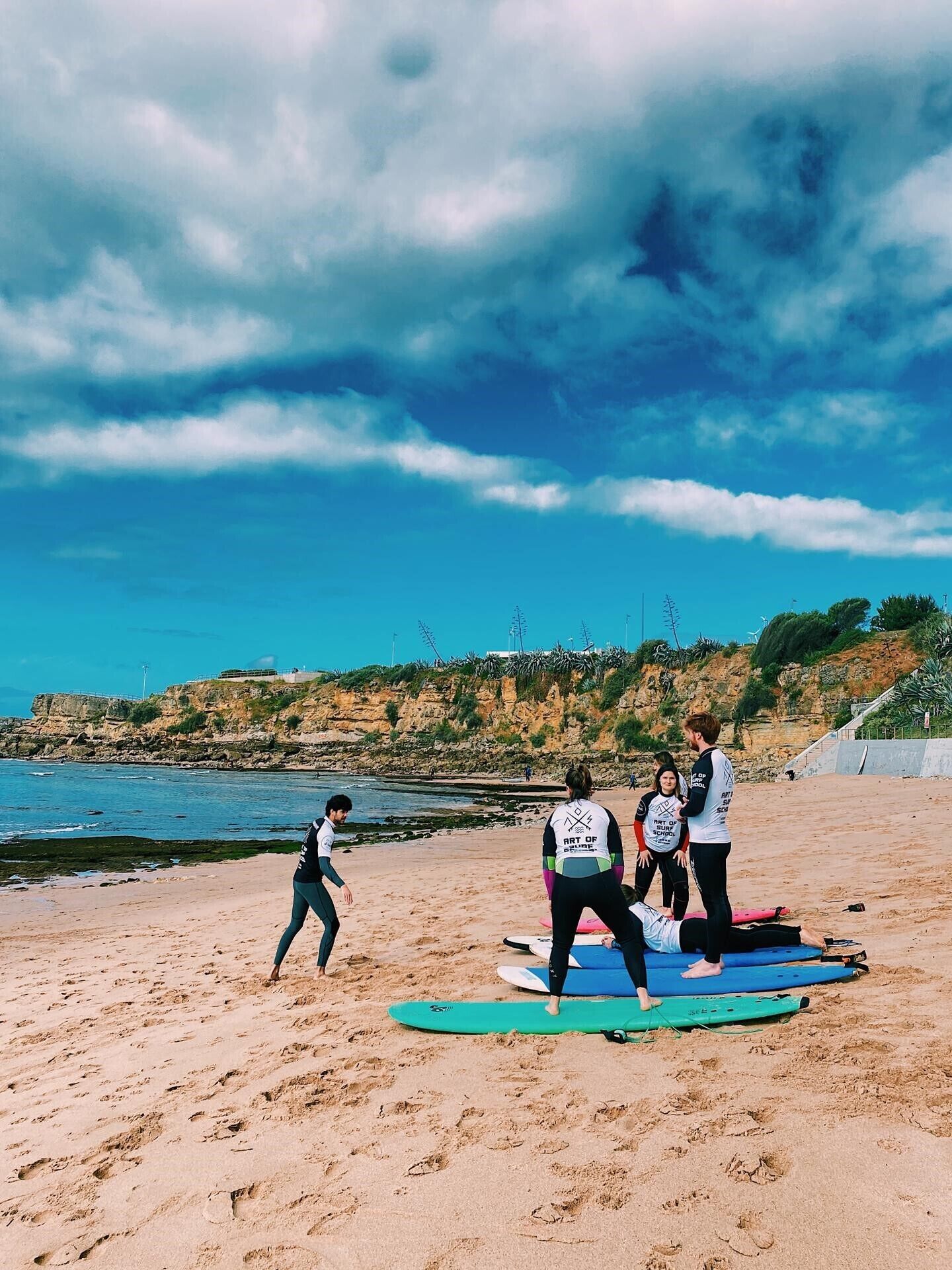 A beach with people practicing surfing on surfboards.