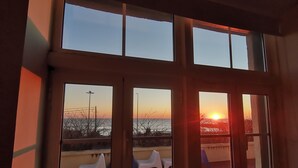 Ein Zimmer mit großen Fenstern und Blick auf einen Sonnenuntergang.