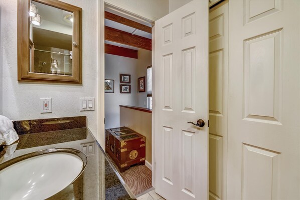 A bathroom with a large mirror, a sink, and a vanity. There is a wooden chest of drawers and a white door. - Tahoe City Getaway Condo (Tahoe City)
