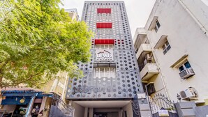 A hotel entrance with a modern facade, a sign for 'UPAR HOTELS', and a gated driveway.