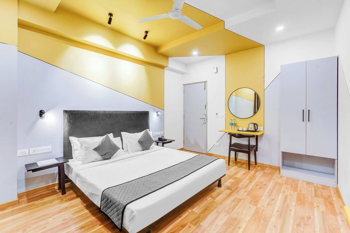 A modern bedroom with a bed, bedside table, nightstand, wardrobe, and a mirror.
