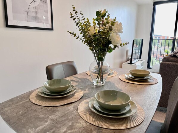 A dining table with a vase of flowers, green plates, and a modern interior. - Impressive 1 Bed Apartment - Chavasse Apartments (Liverpool)