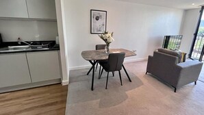 Una cocina moderna con gabinetes grises, una mesa de comedor con sillas, un florero con flores y un sofá gris.