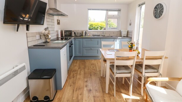 A modern kitchen with a flat-screen TV, a built-in microwave, and a large window. - Croeso (Holyhead)