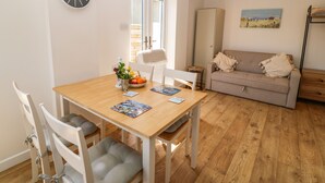 A dining area with a wooden table, white chairs, and a clock on the wall. - Croeso (Holyhead)