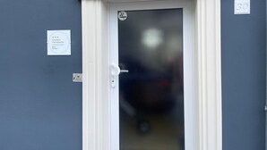 Una porta amb un panell de vidre mossegat, un marc de porta blanc i un petit cartell al mur a l'esquerra.