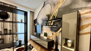A modern living room with a large abstract wall mural, a wooden herringbone floor, and a minimalist shelving unit with decorative items. - Street Living Hotel (Vienna)