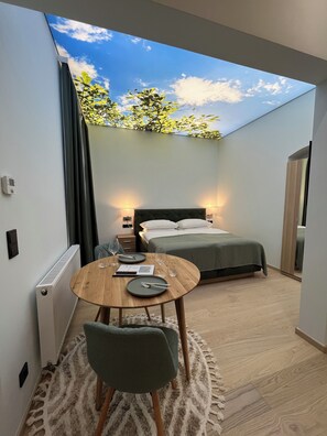 A compact bedroom with a skylight, a bed, bedside tables, and a small round table with a chair. - Street Living Hotel (Vienna)