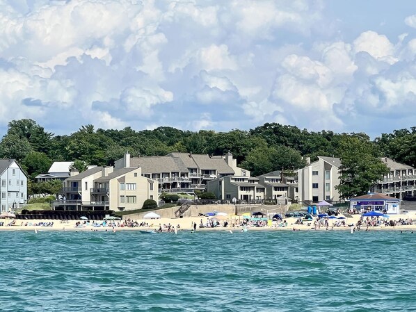 A coastal town with beachfront buildings, a sandy beach, and a clear sky.