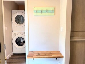 Une buanderie équipée de deux machines à laver et d’une étagère en bois.