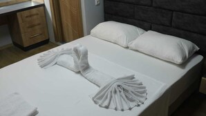 A neatly made bed with white linens and a towel arranged in a fan shape. - Esas Pansiyon (Gemlik)