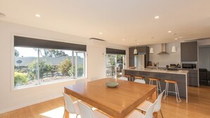 A modern kitchen with a central island, bar stools, and a dining table with chairs.