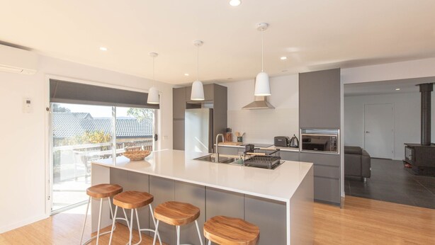 A modern kitchen with a central island, bar stools, a built-in oven, and a stove.